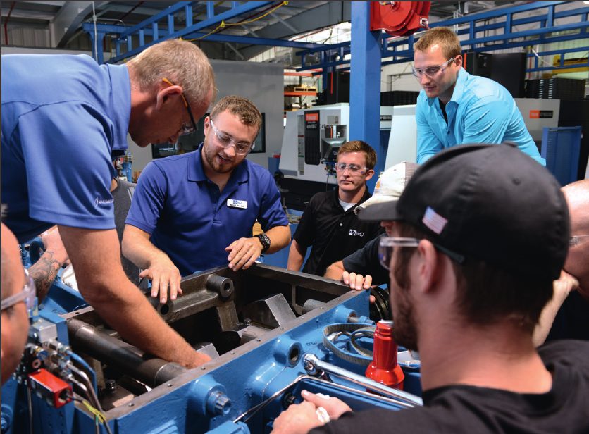A team gathered around a machine on a factory floor